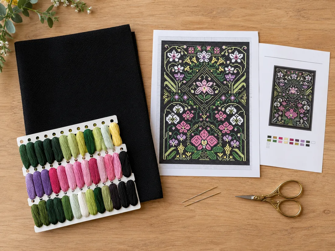 Flat lay of everything in a CozyCross kit laid out on light oak: folded black Aida, pre-sorted cotton threads on an organizer, two needles, the color chart for the Orchid design CC-K8-04 and the instructions, with the scissors set apart