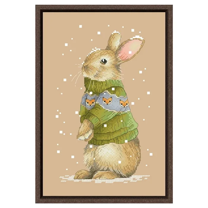 The Rabbit design framed in dark wood: a beige rabbit standing in an olive-green sweater patterned with a row of foxes, with falling snow on flaxen fabric