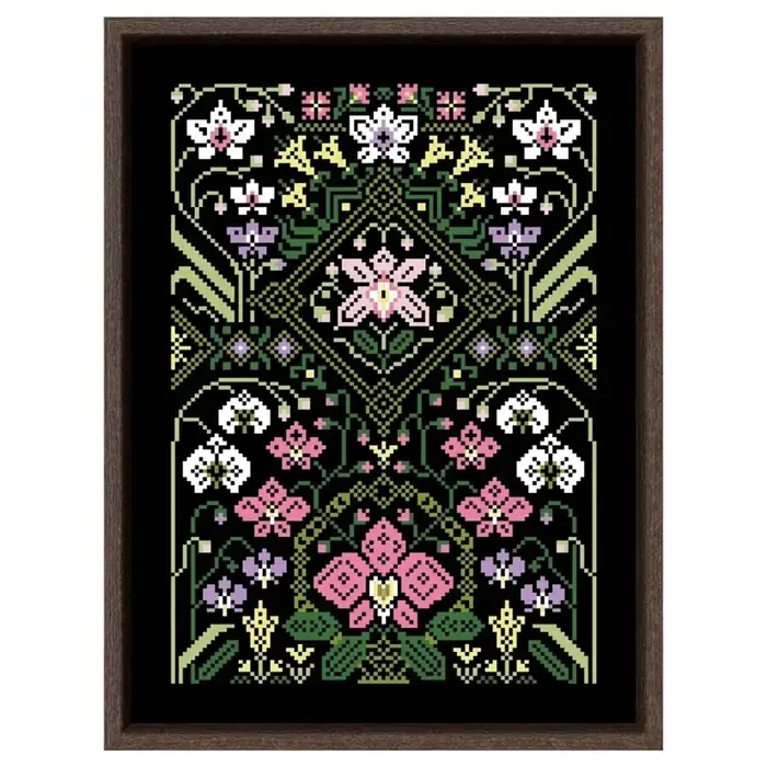 Finished counted cross stitch sampler in a dark wood frame: pink, white, lilac and yellow art nouveau flowers around a green diamond medallion, stitched on black Aida fabric