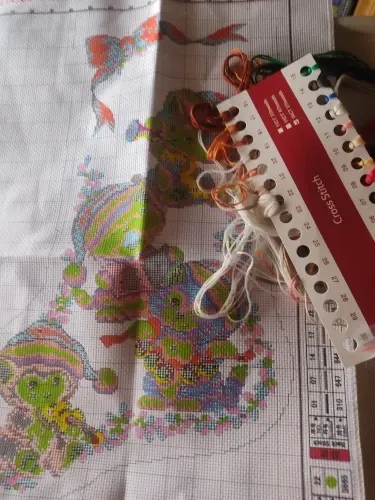 Buyer photo of a stocking mid-stitch: the printed fabric with the Caroling Kittens design, a loaded thread organizer and the chart edge
